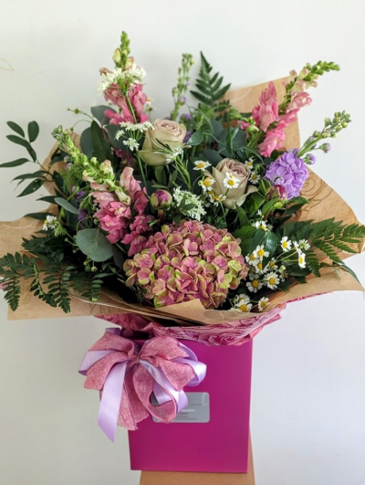 Country Meadow - Bringing the charm of an English country garden to your home, the Country Meadow Bouquet is a beautifully arranged, front-facing bouquet filled with delicate garden-style flowers in soft pinks and lilacs. Designed to look as though it’s been freshly gathered from a meadow, this stunning arrangement is full of natural beauty and rustic elegance.