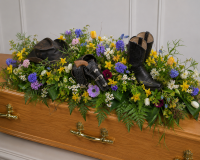 Personalised Tribute - Celebrate the life of someone special with a completely bespoke cowboy-themed casket tribute. Designed using beautiful seasonal flowers in a natural, meadow-inspired style, this unique arrangement can incorporate your loved one's own treasured belongings, creating a truly personal and meaningful farewell.