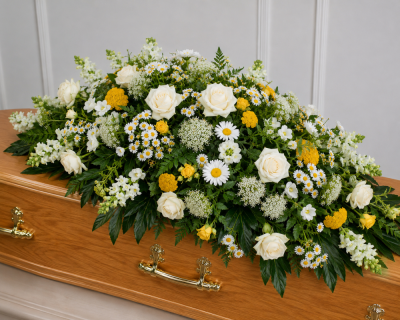 Yellow and white Spray - A beautiful natural-style casket spray featuring elegant white roses, delicate daisies, soft white blooms and cheerful yellow flowers, all nestled amongst fresh seasonal foliage. Designed in a loose, garden-inspired style, this tribute offers a warm and uplifting farewell while celebrating a life filled with love and treasured memories.